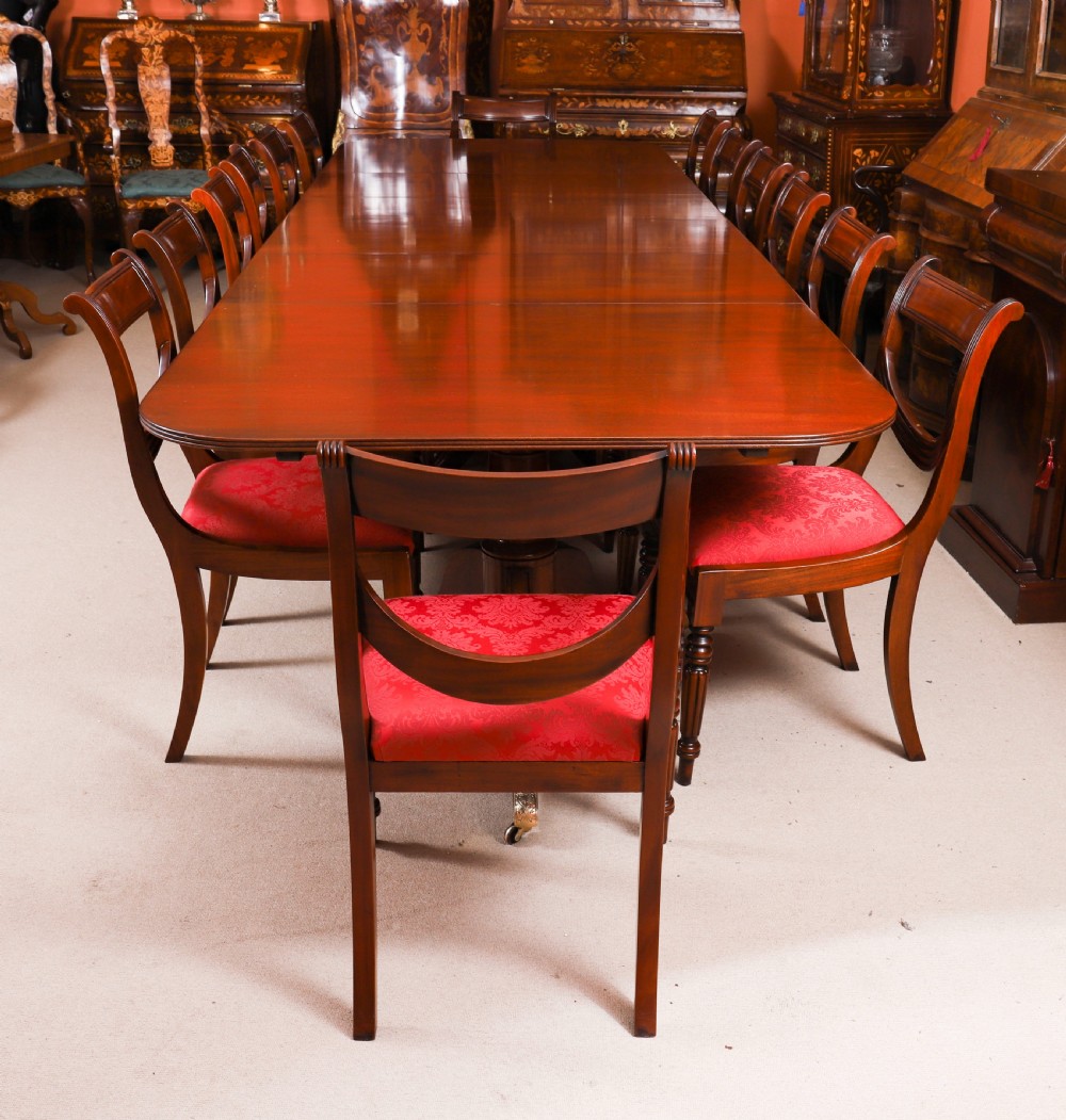 A long polished mahogany triple pillar dining table featuring splayed tripod legs fitted with brass castors. View II