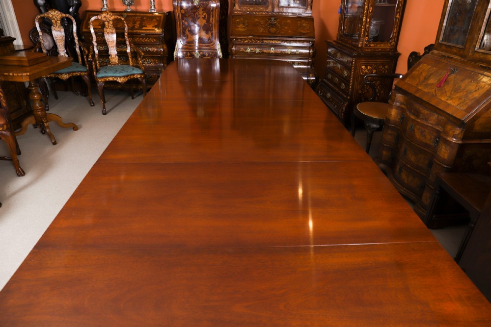 A long polished mahogany triple pillar dining table featuring splayed tripod legs fitted with brass castors. View VI