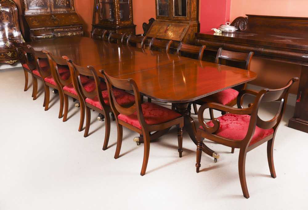 A long polished mahogany triple pillar dining table featuring splayed tripod legs fitted with brass castors. View X