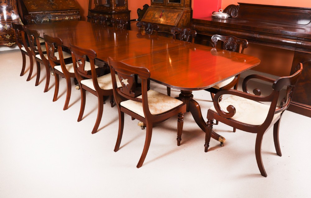 A long polished mahogany triple pillar dining table featuring splayed tripod legs fitted with brass castors. View XV