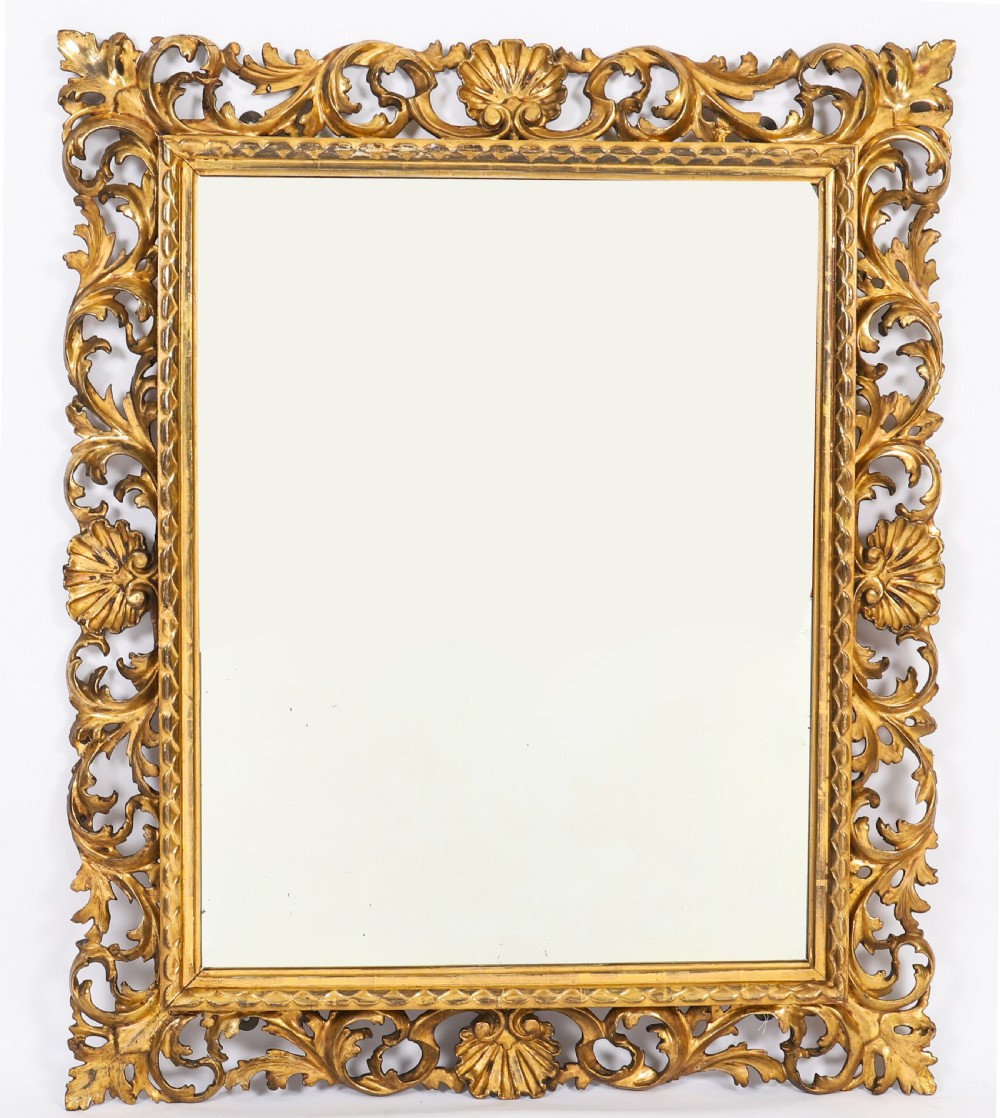 A rectangular 19th-century Italian giltwood wall mirror featuring an openwork frame carved with acanthus leaf scrolls and shell motifs.