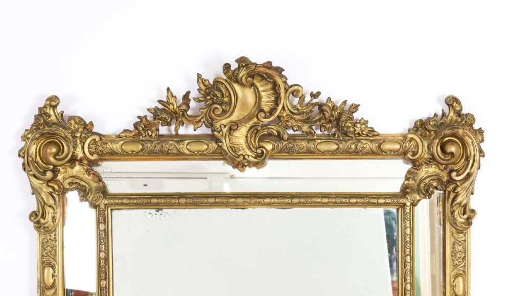 An antique French Louis Revival giltwood cushion overmantel mirror featuring a carved cresting, beaded inner frame, and marginal glass borders. View II