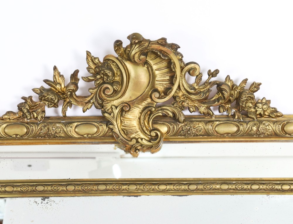 An antique French Louis Revival giltwood cushion overmantel mirror featuring a carved cresting, beaded inner frame, and marginal glass borders. View III