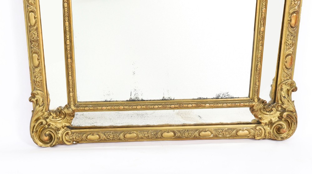 An antique French Louis Revival giltwood cushion overmantel mirror featuring a carved cresting, beaded inner frame, and marginal glass borders. View V
