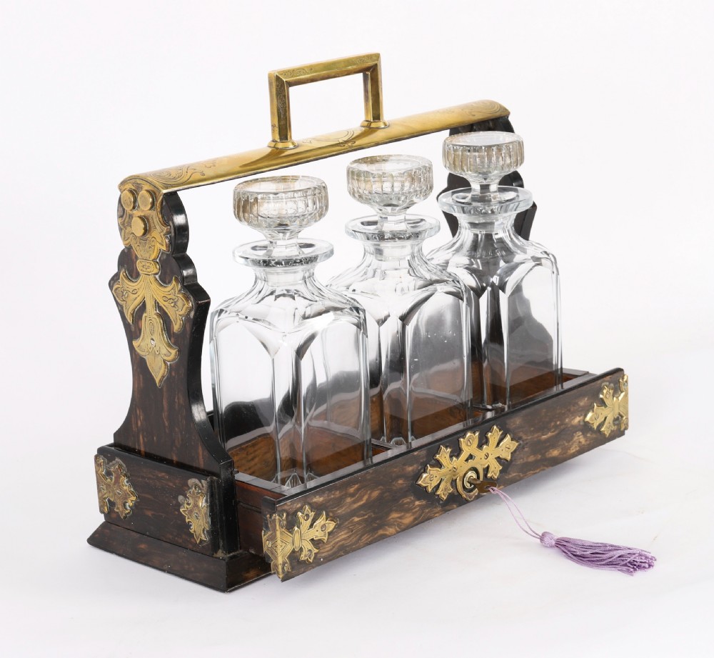 A Victorian coromandel wood tantalus with pierced brass corner mounts and top handle containing three cut crystal decanters with matching stoppers. View VIII