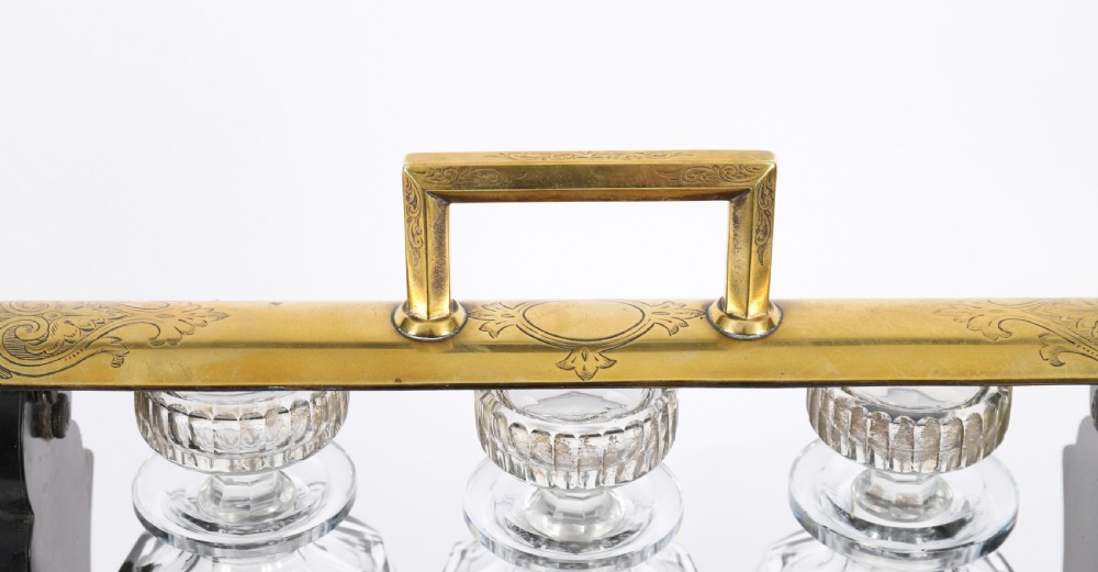 A Victorian coromandel wood tantalus with pierced brass corner mounts and top handle containing three cut crystal decanters with matching stoppers. View XII