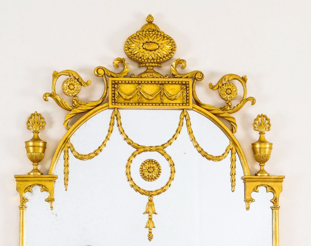 A matching pair of tall 19th-century Neoclassical giltwood pier mirrors decorated with urn crests, draped swags, and rosette motifs. View IV