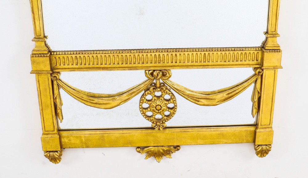 A matching pair of tall 19th-century Neoclassical giltwood pier mirrors decorated with urn crests, draped swags, and rosette motifs. View VIII