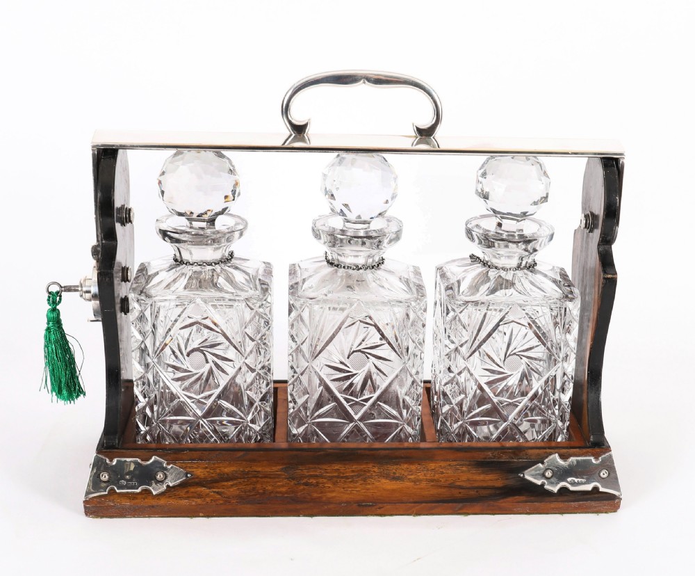 An Edwardian Betjemanns coromandel wood tantalus with hallmarked silver mounts holding three cut-crystal decanters. View III