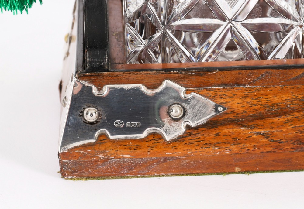 An Edwardian Betjemanns coromandel wood tantalus with hallmarked silver mounts holding three cut-crystal decanters. View XII
