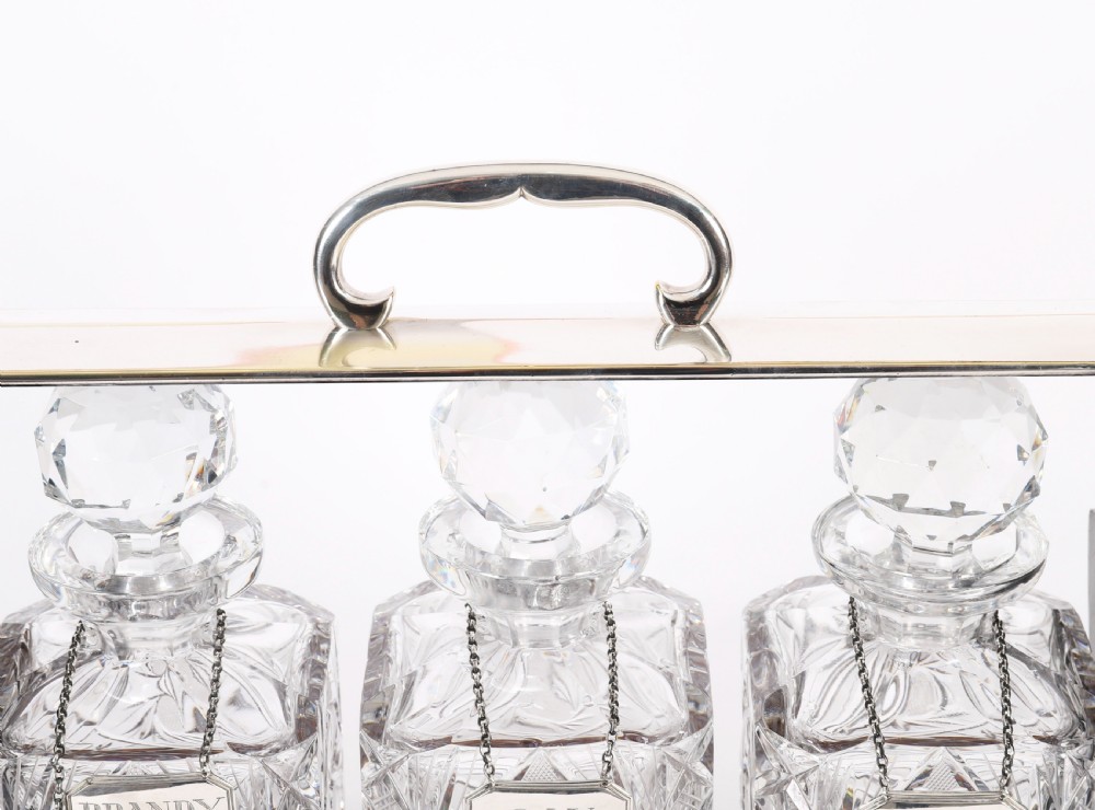 An Edwardian Betjemanns coromandel wood tantalus with hallmarked silver mounts holding three cut-crystal decanters. View XV