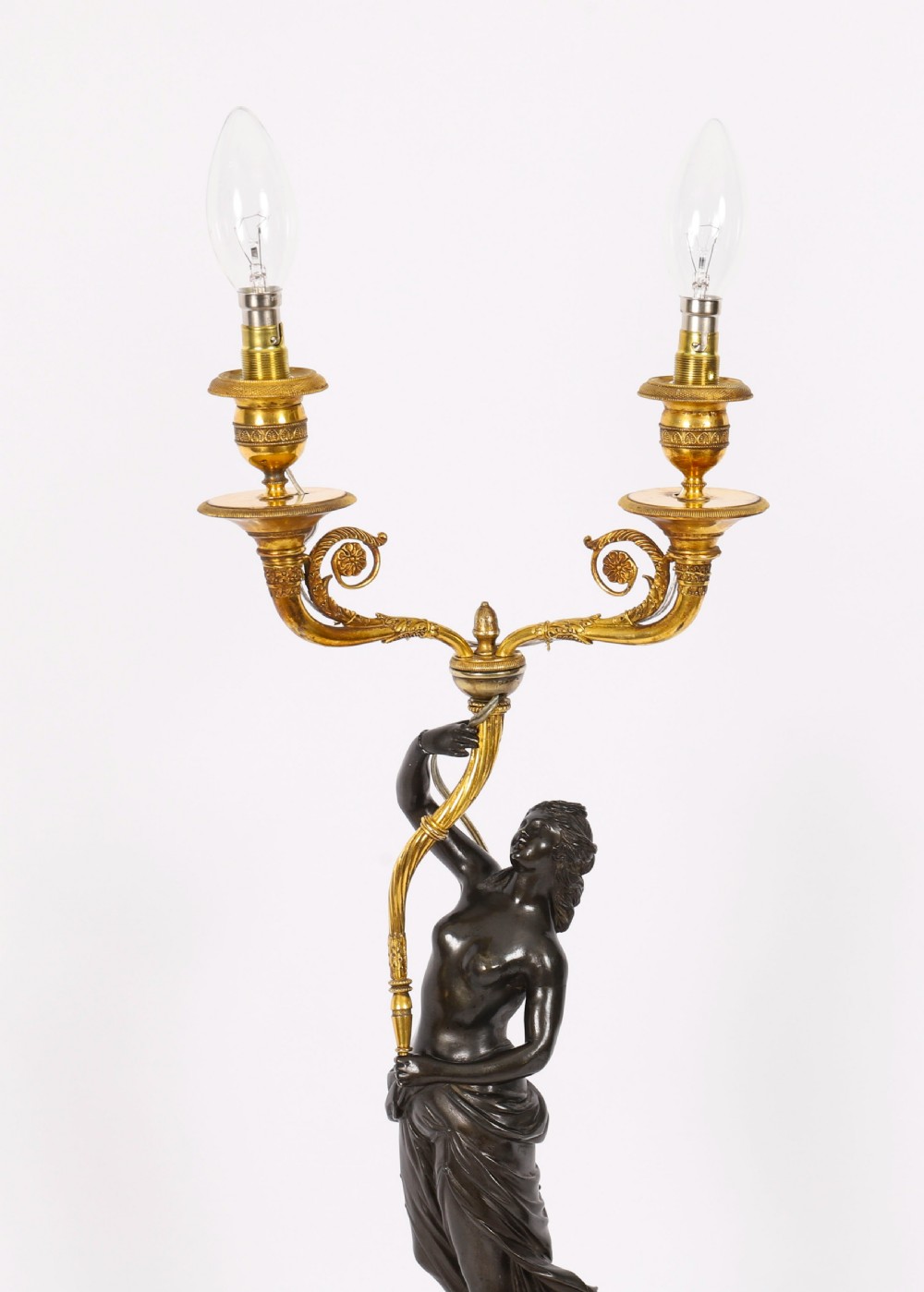 A pair of 19th-century French patinated bronze and gilt bronze two-light candelabra featuring classical draped female figures on cylindrical bases. View II