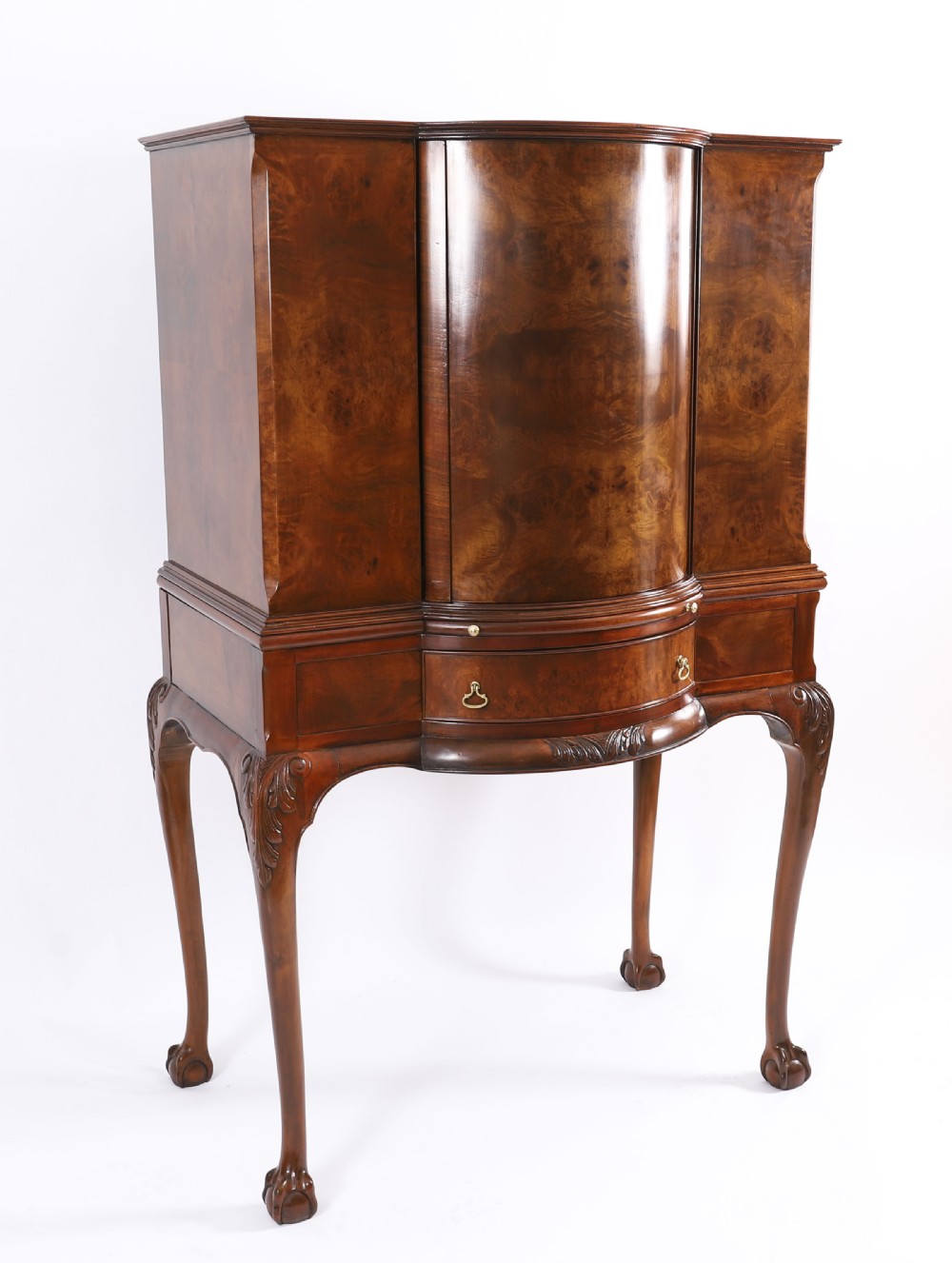A high-standing burr walnut revolving cocktail cabinet raised on cabriole legs with carved knees and claw-and-ball feet.