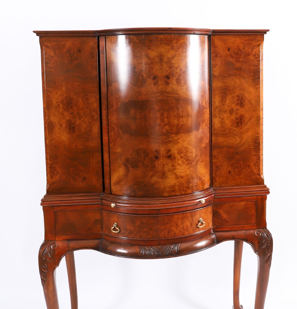 A high-standing burr walnut revolving cocktail cabinet raised on cabriole legs with carved knees and claw-and-ball feet. View IV