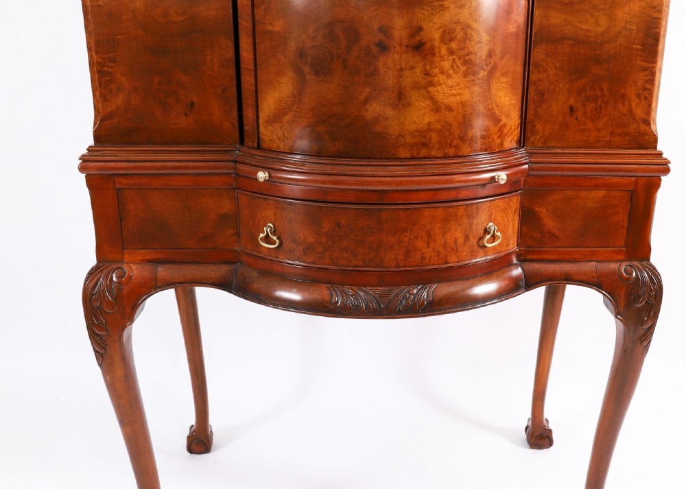 A high-standing burr walnut revolving cocktail cabinet raised on cabriole legs with carved knees and claw-and-ball feet. View V
