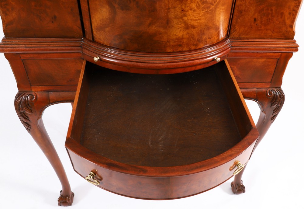 A high-standing burr walnut revolving cocktail cabinet raised on cabriole legs with carved knees and claw-and-ball feet. View IX