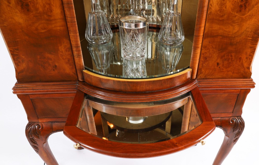 A high-standing burr walnut revolving cocktail cabinet raised on cabriole legs with carved knees and claw-and-ball feet. View X