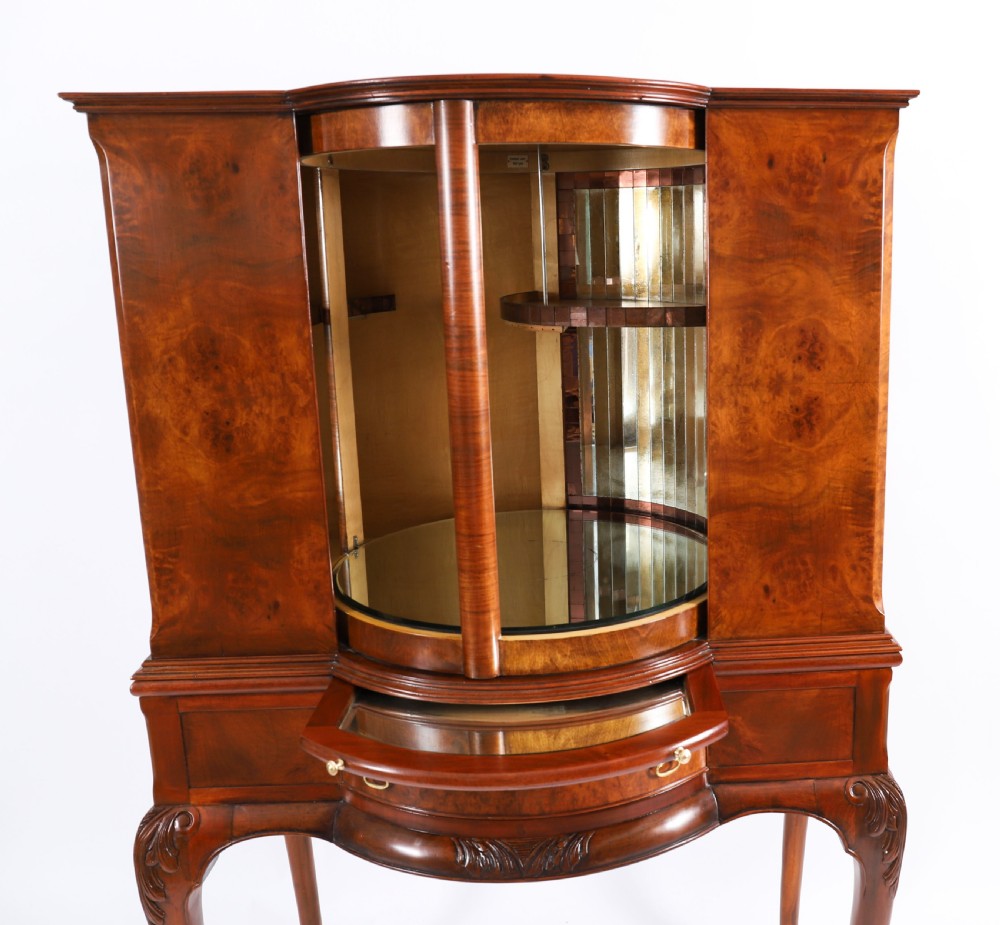 A high-standing burr walnut revolving cocktail cabinet raised on cabriole legs with carved knees and claw-and-ball feet. View XI