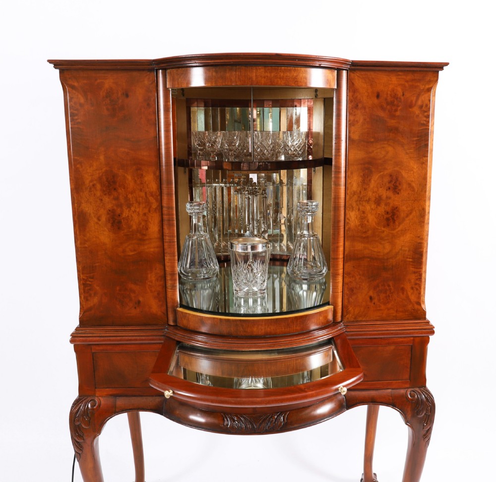 A high-standing burr walnut revolving cocktail cabinet raised on cabriole legs with carved knees and claw-and-ball feet. View XIV