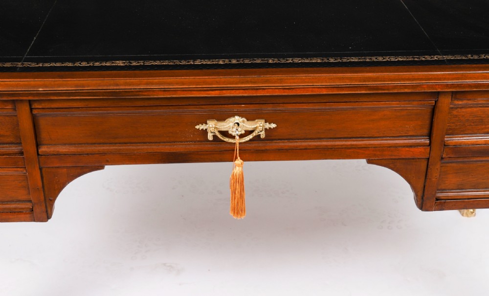A nineteenth-century French Empire style mahogany bureau plat featuring gilt bronze ormolu mounts, tapered legs, five drawers, and a black leather writing surface. View V
