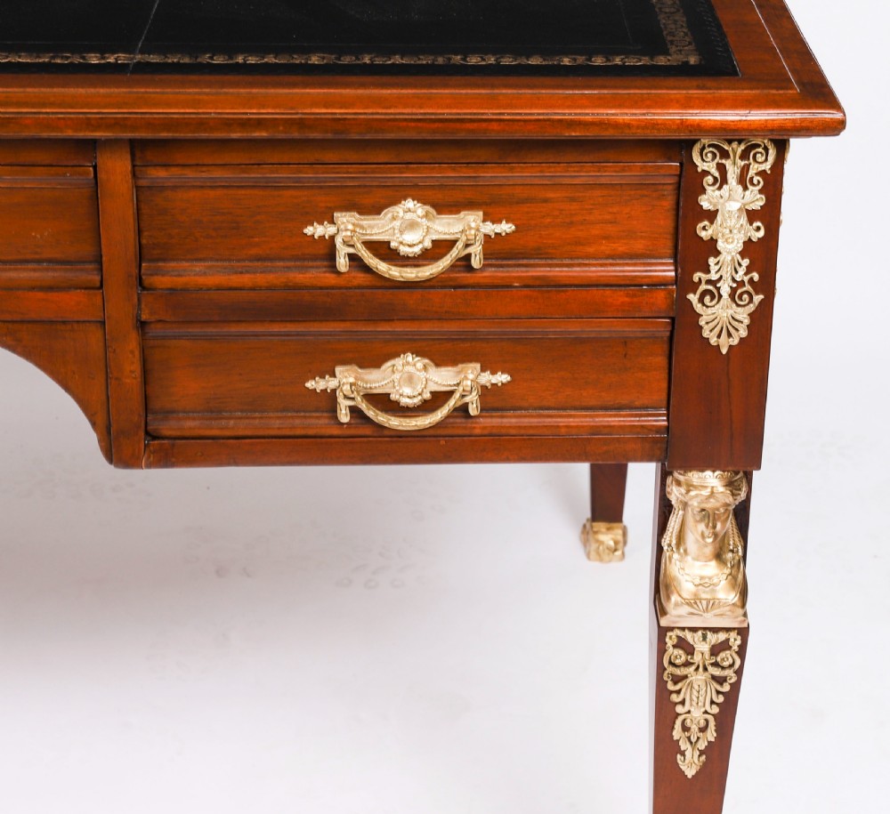 A nineteenth-century French Empire style mahogany bureau plat featuring gilt bronze ormolu mounts, tapered legs, five drawers, and a black leather writing surface. View VII