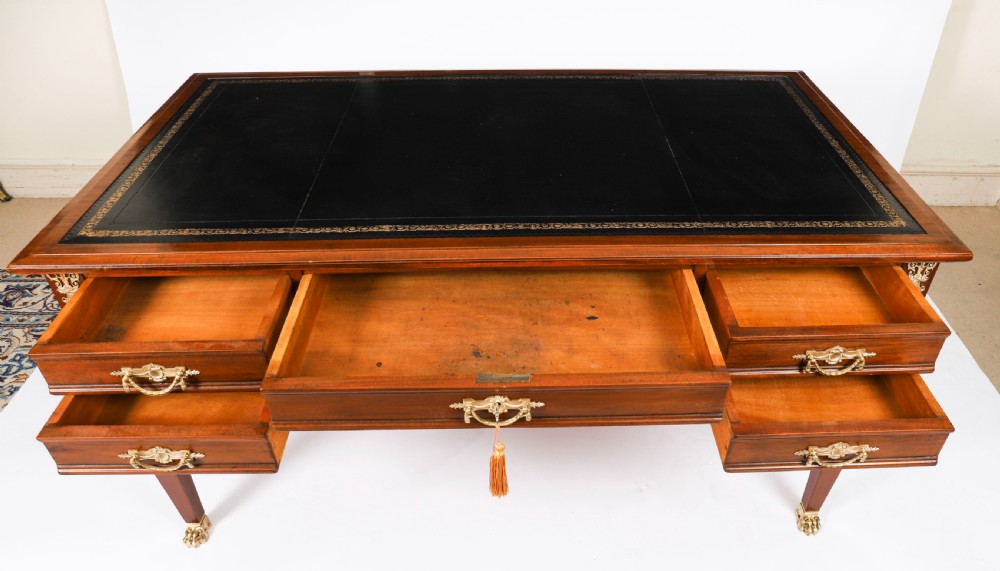 A nineteenth-century French Empire style mahogany bureau plat featuring gilt bronze ormolu mounts, tapered legs, five drawers, and a black leather writing surface. View XII