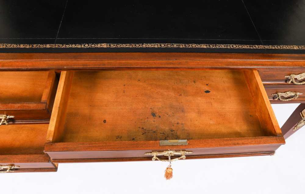 A nineteenth-century French Empire style mahogany bureau plat featuring gilt bronze ormolu mounts, tapered legs, five drawers, and a black leather writing surface. View XIII