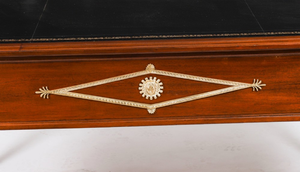 A nineteenth-century French Empire style mahogany bureau plat featuring gilt bronze ormolu mounts, tapered legs, five drawers, and a black leather writing surface. View XVII