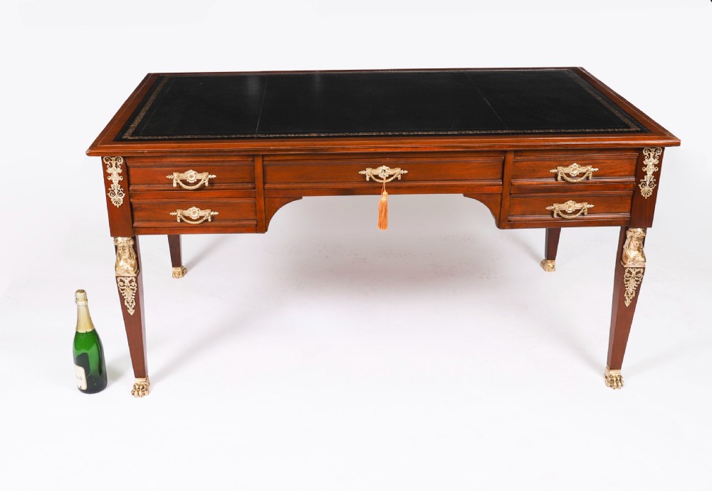 A nineteenth-century French Empire style mahogany bureau plat featuring gilt bronze ormolu mounts, tapered legs, five drawers, and a black leather writing surface. View XIX