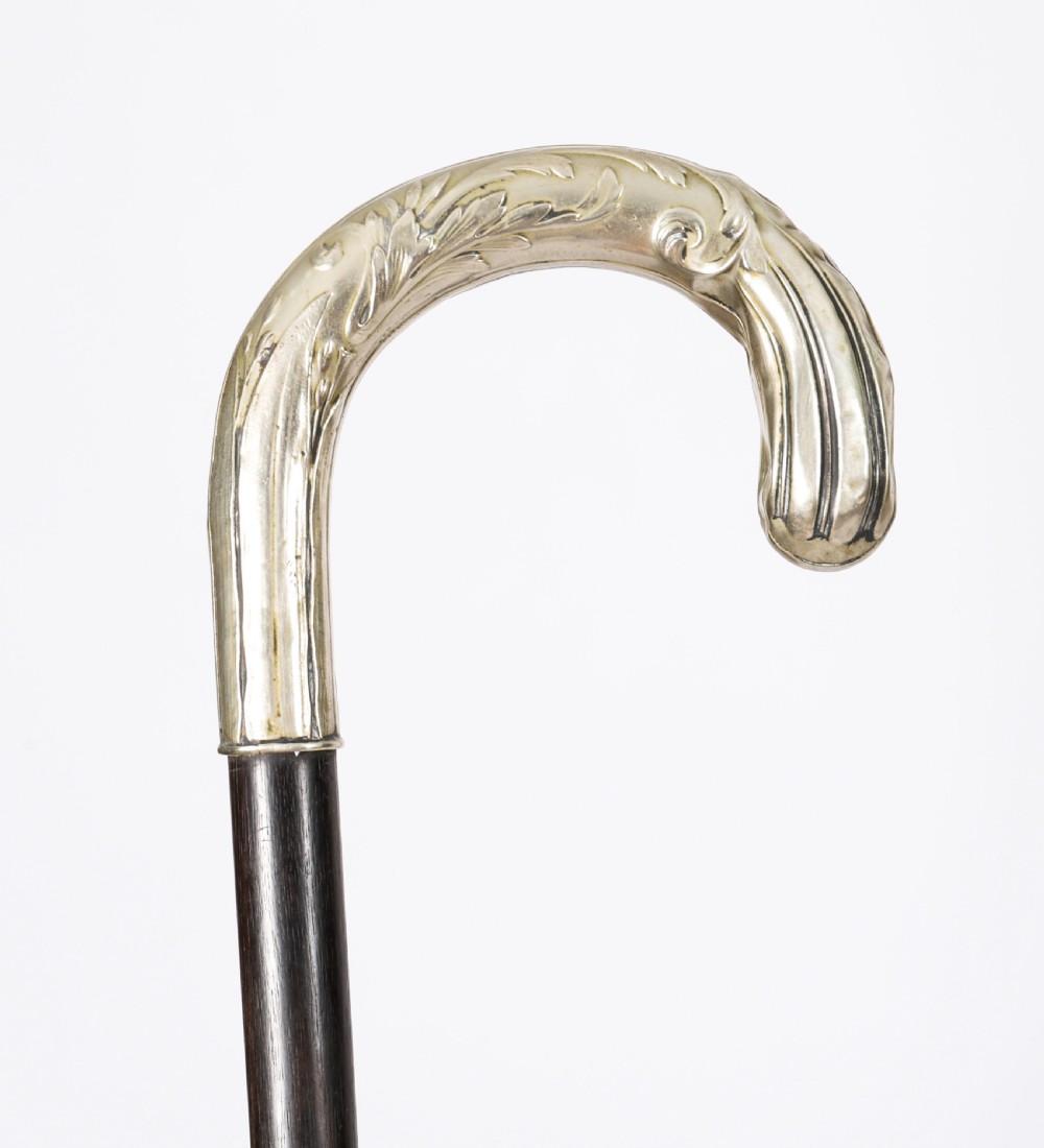 A 19th-century French Art Nouveau walking cane featuring a silver-plated crook handle decorated with foliate reliefs attached to a dark wooden shaft.