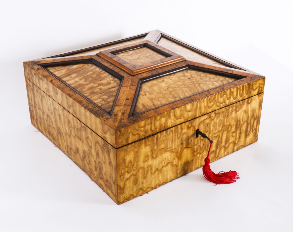 A square Victorian casket constructed with figured burr maple veneer and raised geometric burr walnut mouldings, complete with a lock and red tassel.