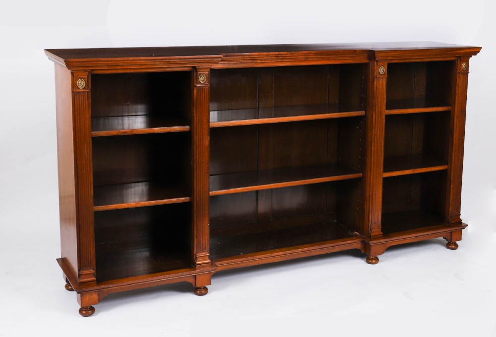 A wide Victorian open bookcase crafted in dark polished walnut with three bays of adjustable shelves, fluted pilasters adorned with circular ormolu mounts, and short turned feet. View II