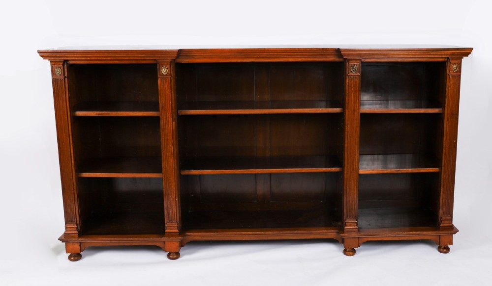 A wide Victorian open bookcase crafted in dark polished walnut with three bays of adjustable shelves, fluted pilasters adorned with circular ormolu mounts, and short turned feet. View IV