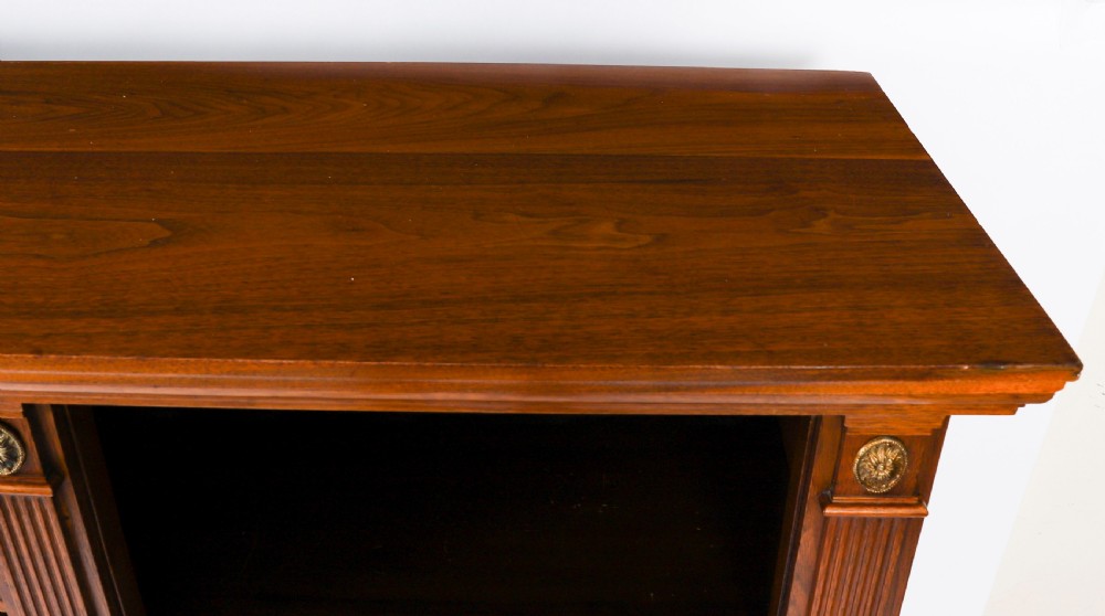 A wide Victorian open bookcase crafted in dark polished walnut with three bays of adjustable shelves, fluted pilasters adorned with circular ormolu mounts, and short turned feet. View VII
