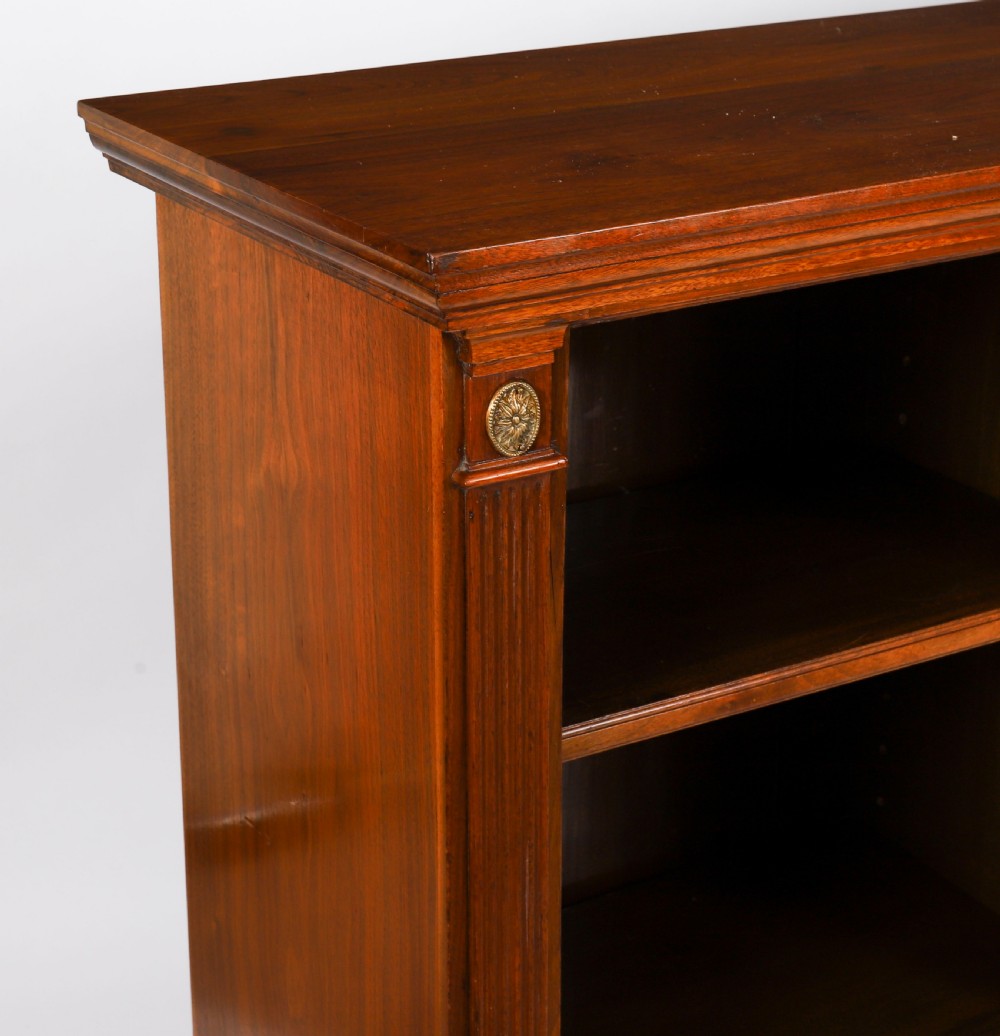 A wide Victorian open bookcase crafted in dark polished walnut with three bays of adjustable shelves, fluted pilasters adorned with circular ormolu mounts, and short turned feet. View IX