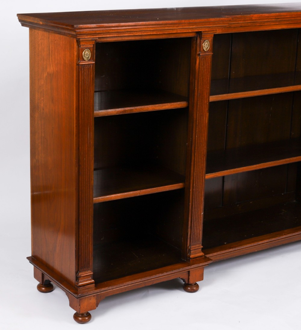 A wide Victorian open bookcase crafted in dark polished walnut with three bays of adjustable shelves, fluted pilasters adorned with circular ormolu mounts, and short turned feet. View XI