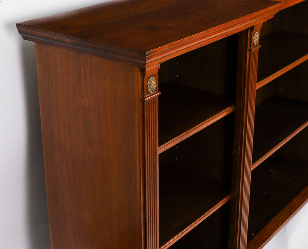 A wide Victorian open bookcase crafted in dark polished walnut with three bays of adjustable shelves, fluted pilasters adorned with circular ormolu mounts, and short turned feet. View XII