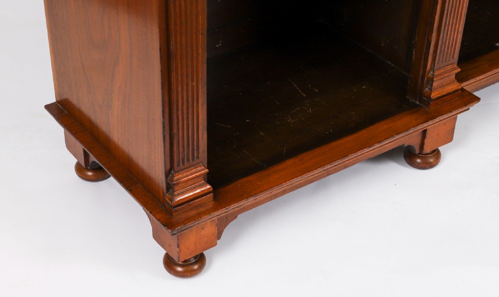 A wide Victorian open bookcase crafted in dark polished walnut with three bays of adjustable shelves, fluted pilasters adorned with circular ormolu mounts, and short turned feet. View XIV