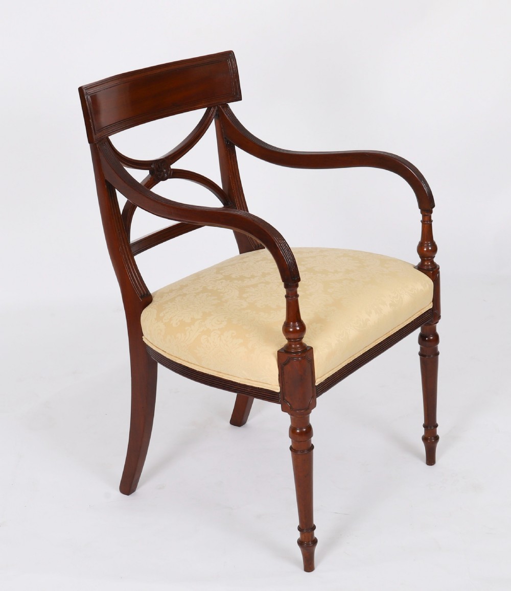 A set of eight Regency mahogany dining chairs with carved X-frame splats, reeded turned front legs, and light damask upholstered seats. View III