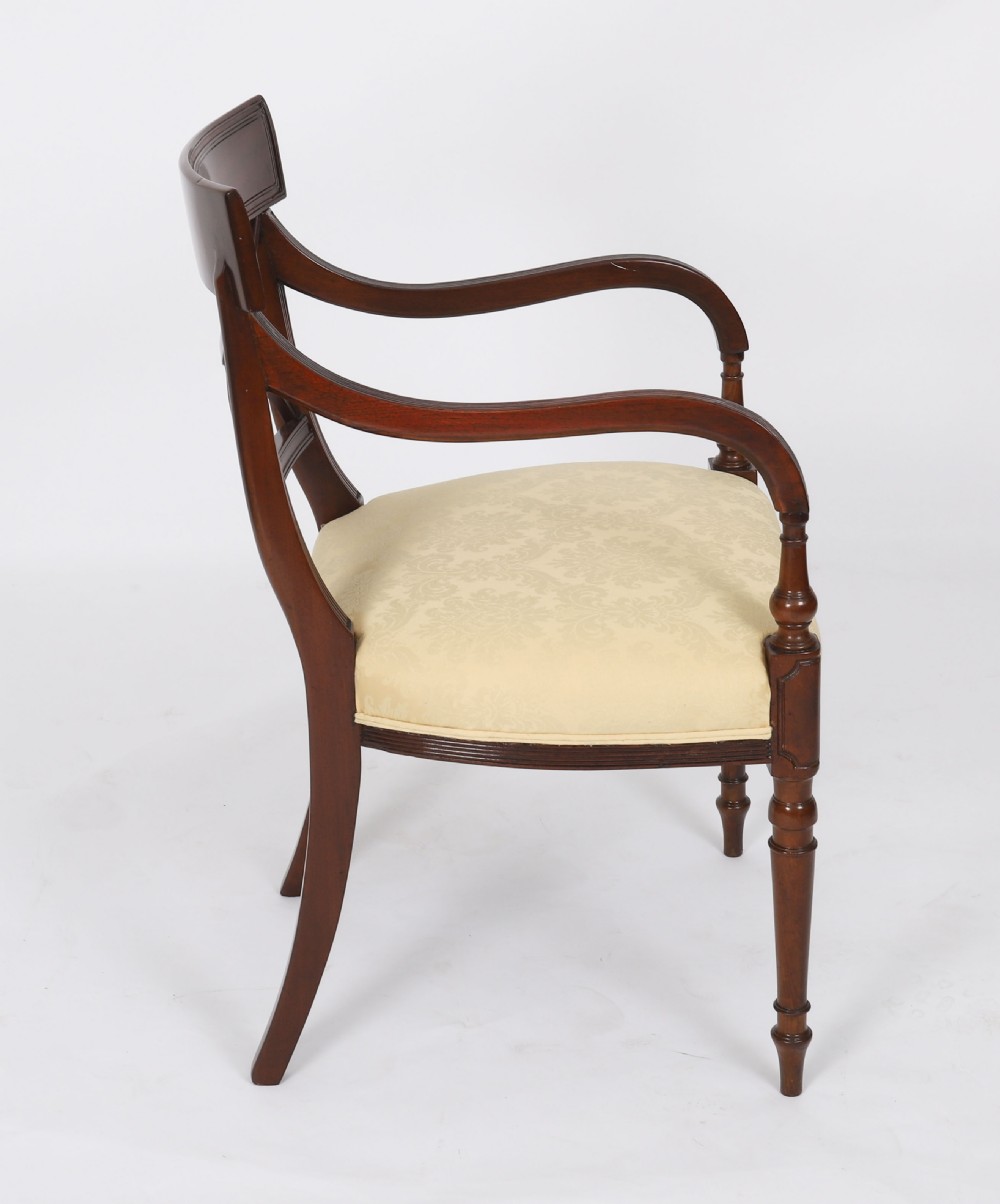 A set of eight Regency mahogany dining chairs with carved X-frame splats, reeded turned front legs, and light damask upholstered seats. View IV