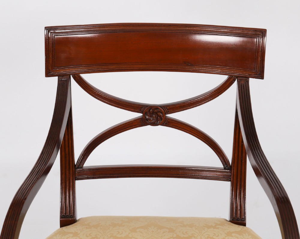 A set of eight Regency mahogany dining chairs with carved X-frame splats, reeded turned front legs, and light damask upholstered seats. View VI
