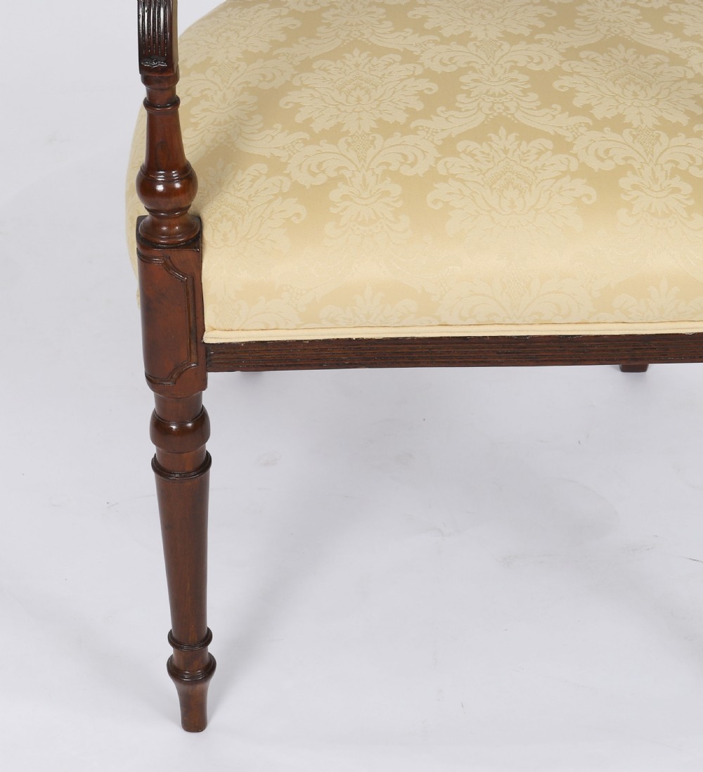A set of eight Regency mahogany dining chairs with carved X-frame splats, reeded turned front legs, and light damask upholstered seats. View IX