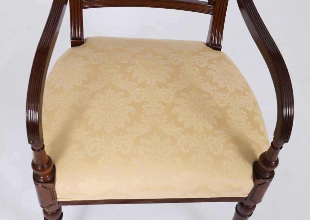 A set of eight Regency mahogany dining chairs with carved X-frame splats, reeded turned front legs, and light damask upholstered seats. View X