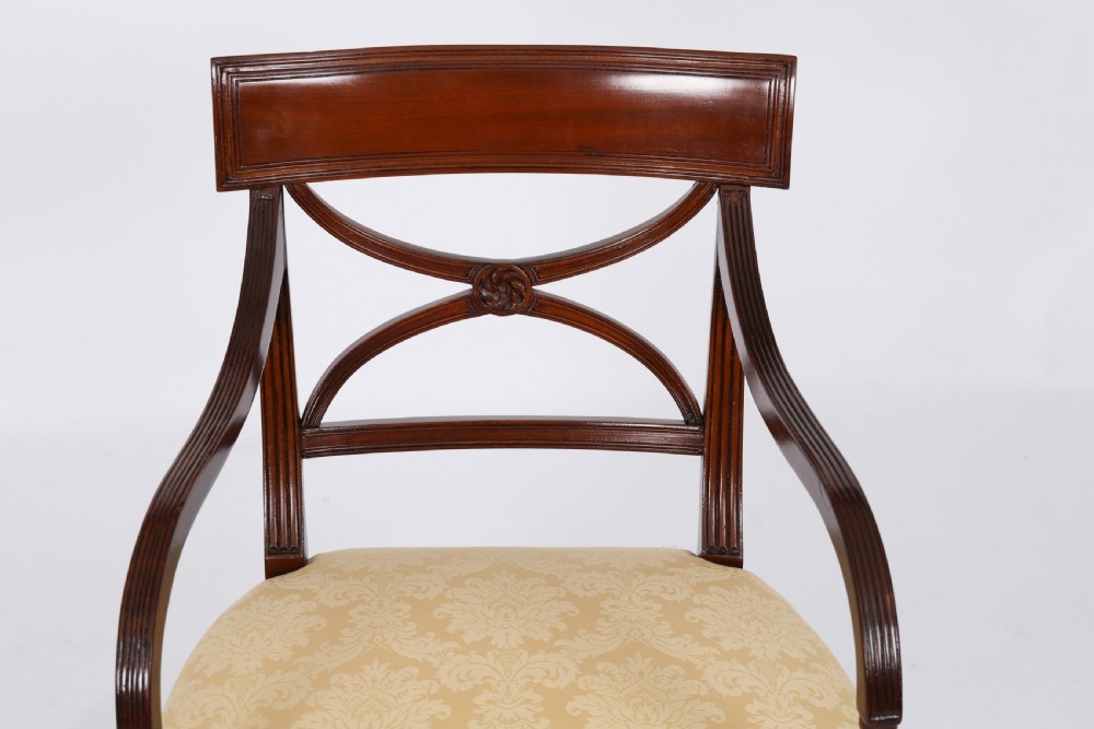 A set of eight Regency mahogany dining chairs with carved X-frame splats, reeded turned front legs, and light damask upholstered seats. View XI