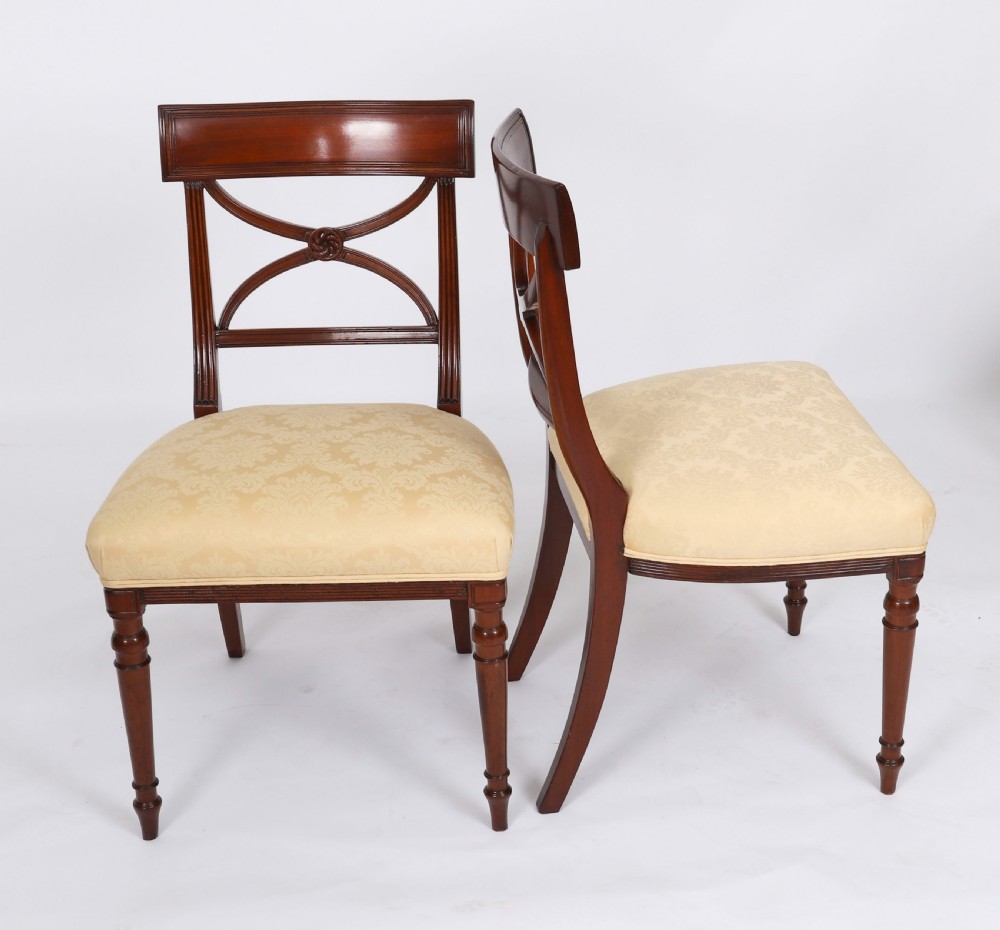 A set of eight Regency mahogany dining chairs with carved X-frame splats, reeded turned front legs, and light damask upholstered seats. View XII