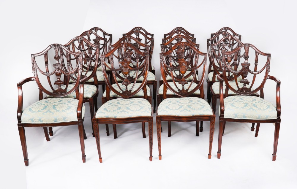 A large set of sixteen mahogany dining chairs featuring carved shield backrests and light blue patterned upholstered seats.
