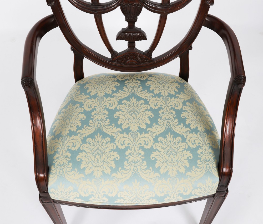 A large set of sixteen mahogany dining chairs featuring carved shield backrests and light blue patterned upholstered seats. View VI