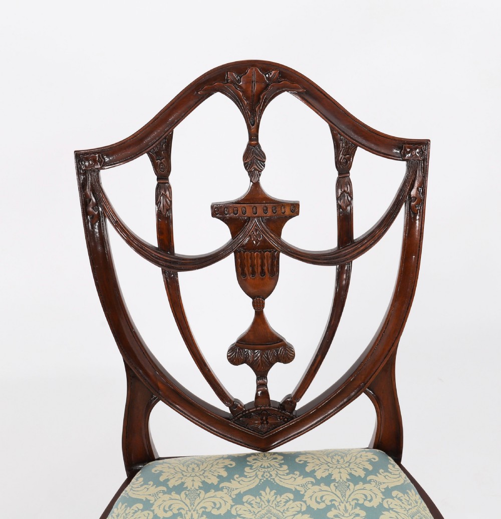 A large set of sixteen mahogany dining chairs featuring carved shield backrests and light blue patterned upholstered seats. View XI
