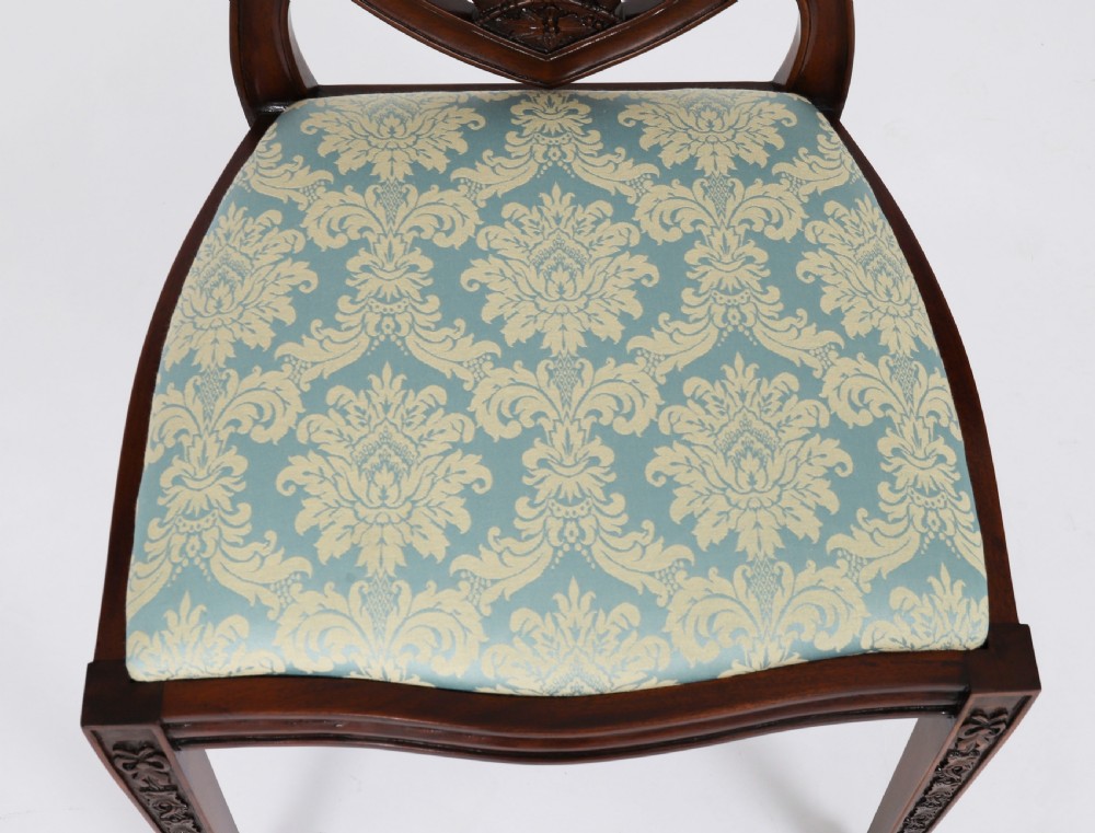 A large set of sixteen mahogany dining chairs featuring carved shield backrests and light blue patterned upholstered seats. View XII