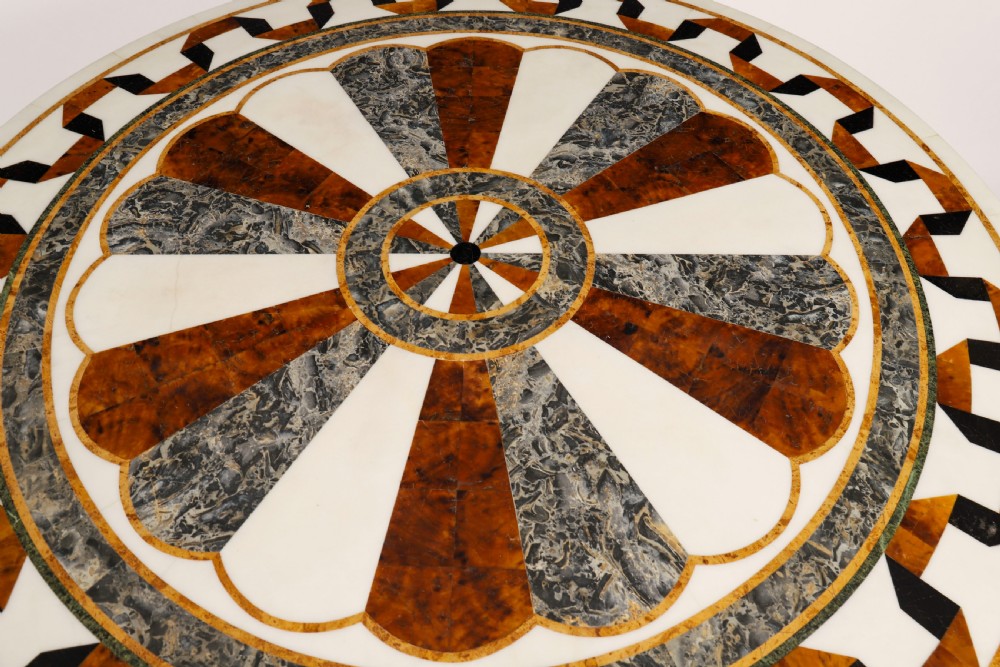 A circular centre table featuring an intricate geometric inlaid marble top supported by three carved gilt dolphin figures on a triform marble base. View III